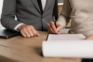 life insurance, image of person signing a document with a man observing