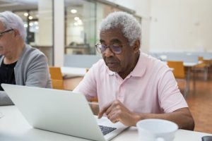 long term care, image of senior man using a laptop indoors